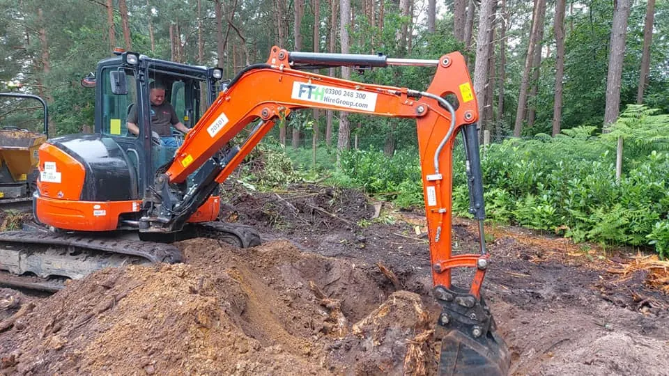 An orange excavator sitting on top of a pile of dirt.