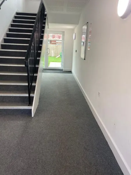 A long hallway with stairs leading up to a door.