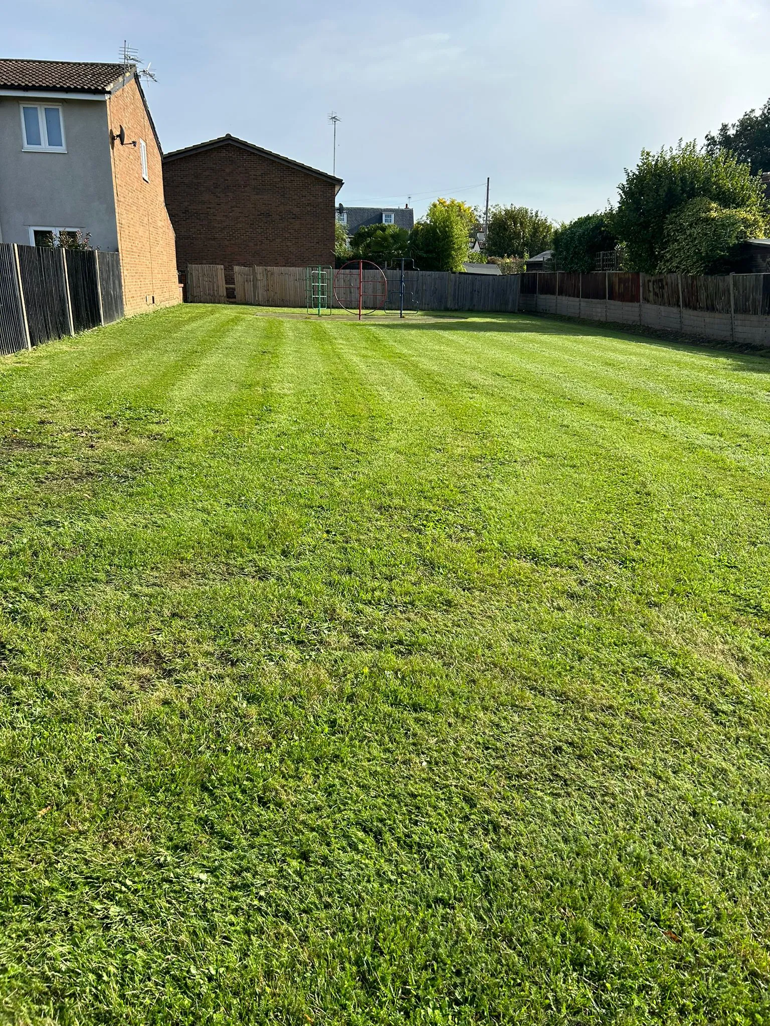 A yard with a fence and a house in the background.